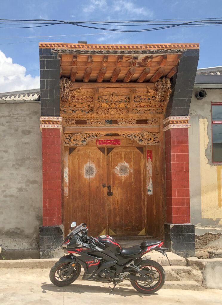 Motorbike in front of carved Tibetan door